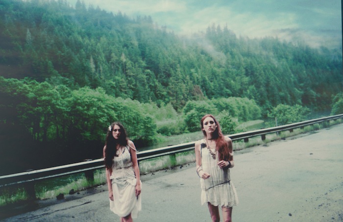 Dos chicas andando por una carretera de un monte