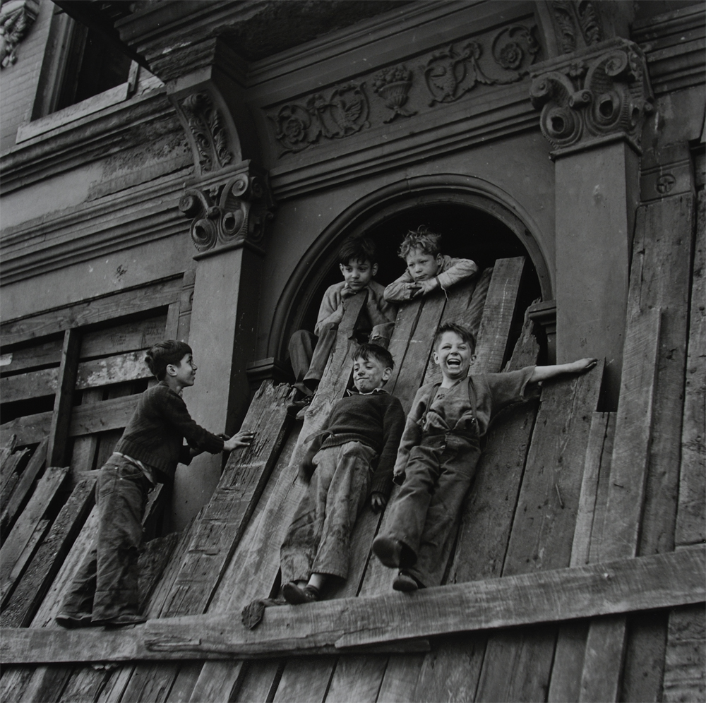 Fotografía de niños subidos a una pared jugando por Jerome liebling 