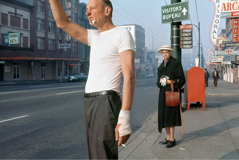 Fotografía de un Hombre pidiendo un taxti con una anciana detrás