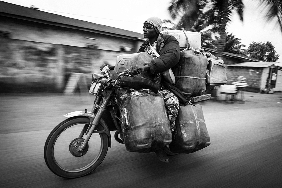 Hombre en moto portando bidones de gasolina