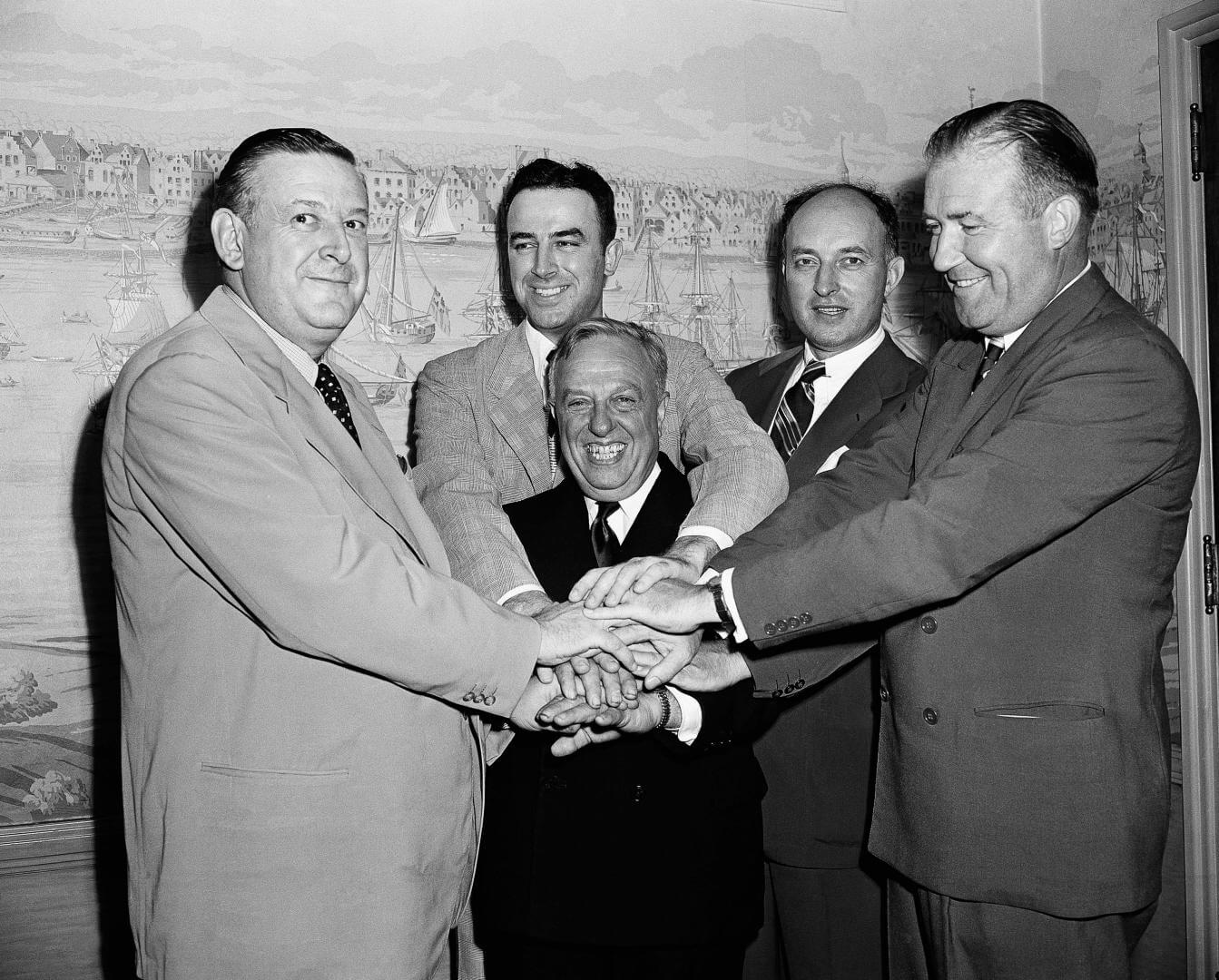 Representatives of the National Basketball League and Basketball Association of America, shake hands after agreeing to a merger of the two circuits into an 18-team organization to be known as the National Basketball Association, Aug 3, 1949, New York. Grouped around the smiling Maurice Podoloff, center, are left to right: Ike Duffey, Leo Ferris, Ned Irish, and Walter Brown. (AP Photo/John Lent)