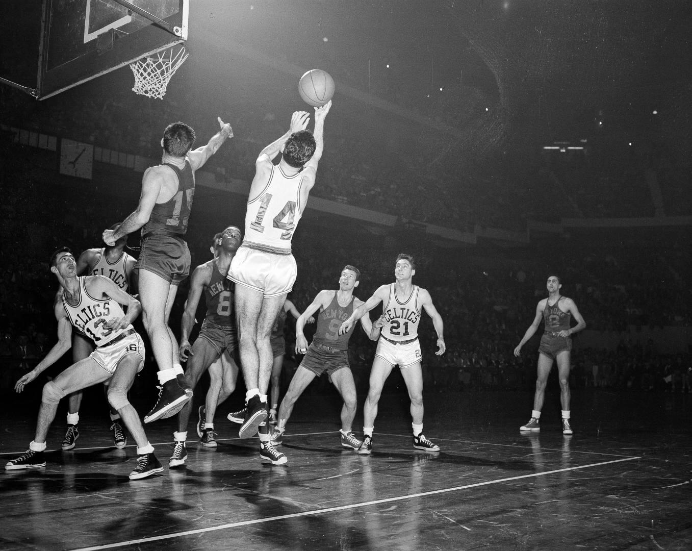 Bob Cousy (14) of the Boston Celtics takes a rebound off the backboard after an attempted basket by Dick McGuire (15) of the New York Knickerbockers in the fourth quarter of their NBA playoff game at the Boston Garden in Boston, Mass., March 26, 1953. Other identifiable players are: Bob Harris (13) and Bill Sharman (21) of the Celtics: Nat Clifton (8) and Ernie Vandeweghe (9) both of the Knicks. The Celtics won 86-70. (AP Photo/Bill Chaplis)