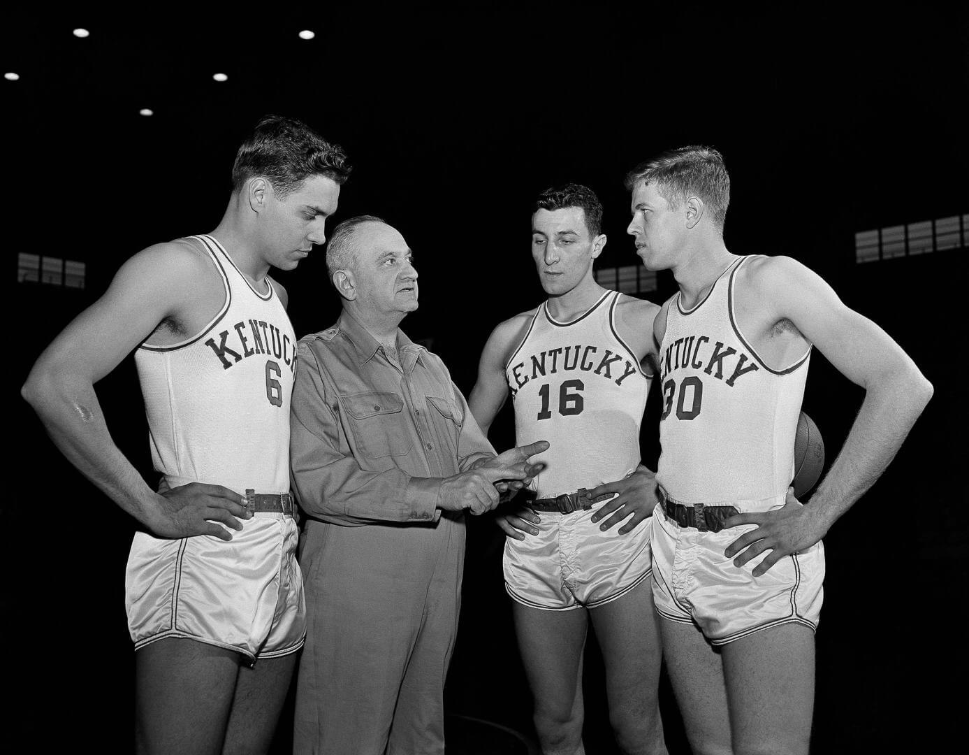 FILE - In this Jan. 16, 1954, file photo, Kentucky basketball coach Adolph Rupp talks to players, from left, Cliff Hagan, Lou Tsioropoulos and Frank Ramsey (30) in Lexington, Ky. Tsioropoulos, a member of Kentucky's 1951 NCAA national championship team and the unbeaten `53-54 squad who went on to win two NBA titles with the Boston Celtics, has died. He was 84. Tsioropoulos' nephew, Michael Johnson, said Wednesday night, Aug. 26, 2015, that his uncle died Saturday in Louisville, Ky., of natural causes. A memorial service was held there Wednesday. He would have turned 85 on Monday. (AP Photo/John Wyatt, File)