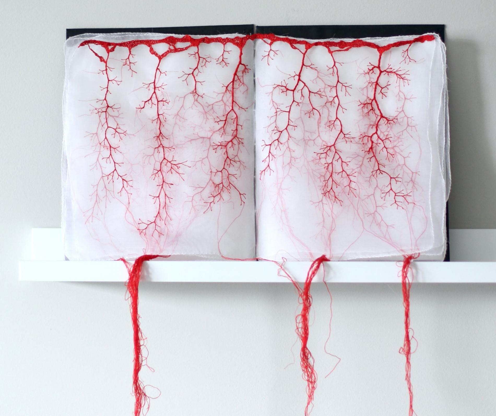 obra textil con hilos rojos en liobros de tela traslucida