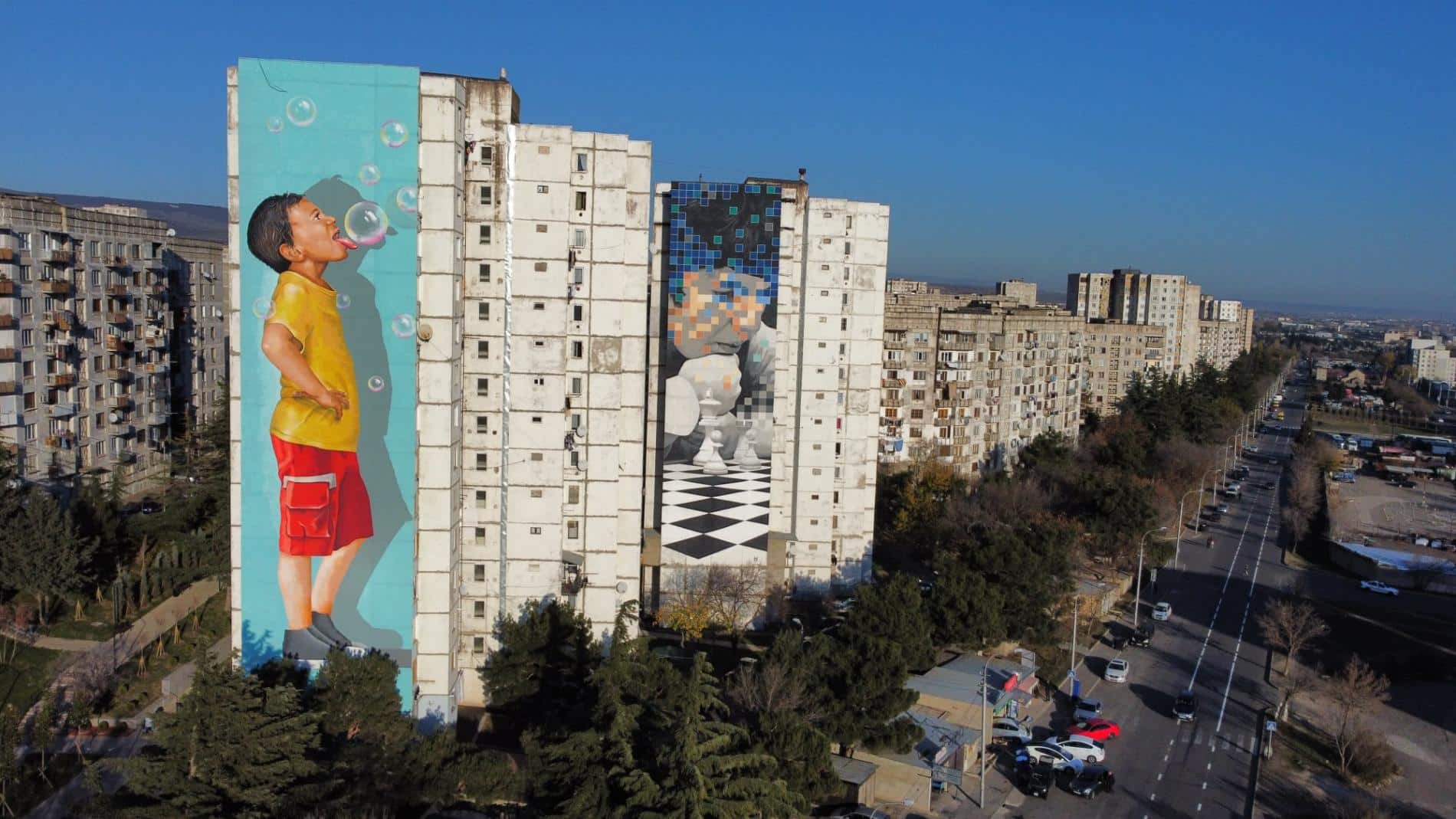 tbilisi mural fest a la dercha mural de niño con burbujas de jabon y al lado izquierdoi mural de pixel Left Kade90. Right David Samkharadze