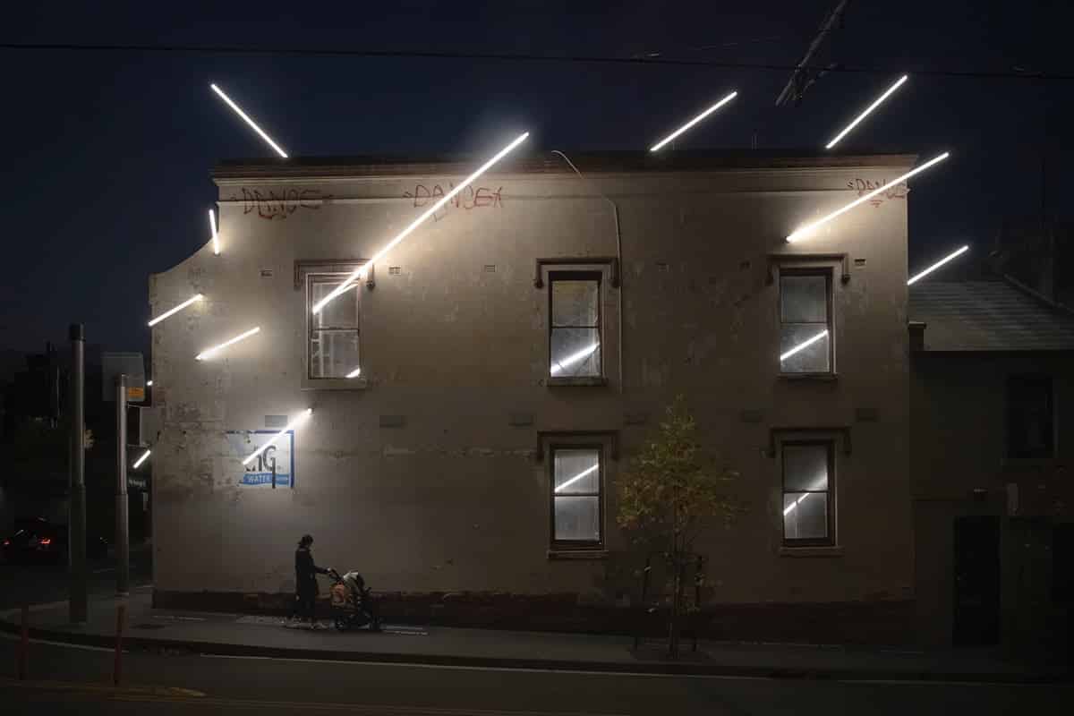 Ian Strange casa iluminada intervencion arquitectonica vista nocturna lateral con transeunte