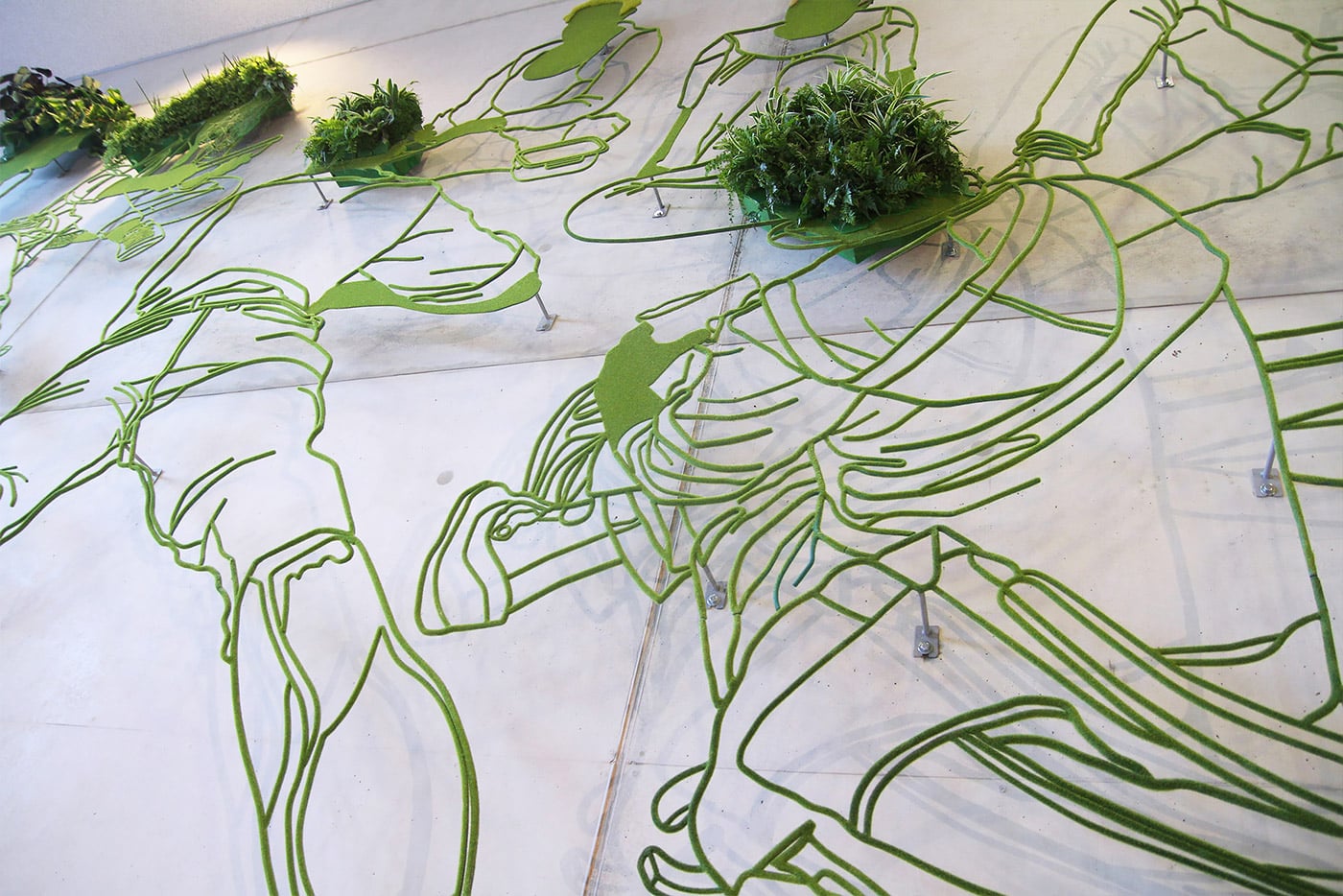 frank plant escultura de foiguras verdes en acero con plantas en detalle